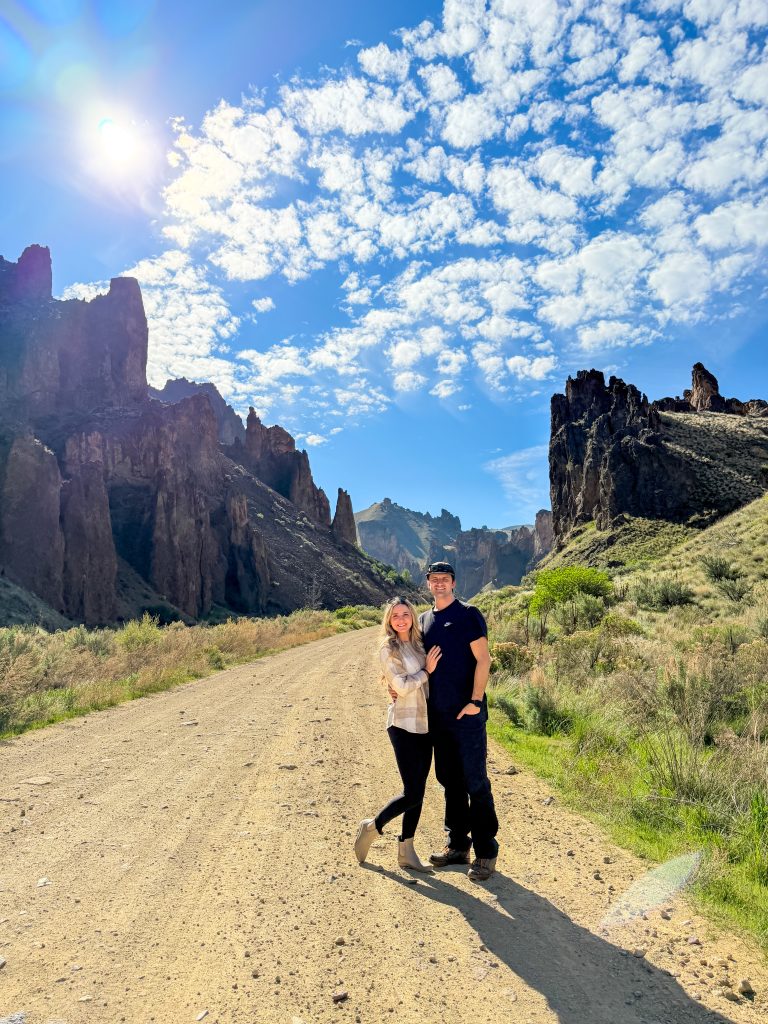 Couple standing on a gravel road surrounded by rock formations at Leslie Gulch, Oregon